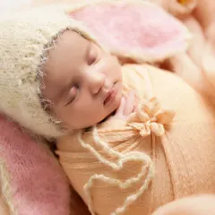 So tiny and perfect in a little bunny hat. We use soft wraps and gentle posing to keep newborns comfortable and sleepy during their first photoshoot.