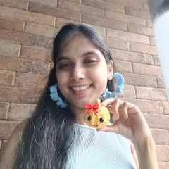 Me holding a cute crochet Modak I made for a contest, while wearing my handmade blue crochet hoop earrings.