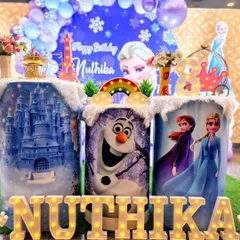 A magical 'Frozen' themed birthday party featuring custom-printed pedestals with characters like Elsa, Anna, and Olaf, marquee letters, and a winter wonderland backdrop.