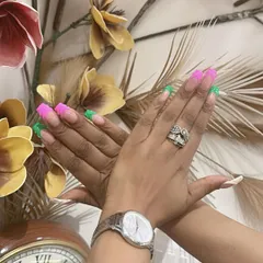 Another view of the eye-catching pink and green French tip manicure. This is a great way to add a pop of color to a classic style.