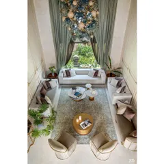 An overhead view of the double-height living room, highlighting the symmetrical furniture arrangement and the grand scale of the space. The large window provides a beautiful view of the garden.