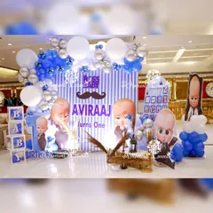 A fun and stylish photo booth for a "Boss Baby" party, with a striped backdrop, character cutouts, and themed balloon arrangements.
