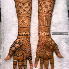A classic full-arm bridal design filled with traditional Indian henna patterns. Notice the rows of elephants for good luck, the blooming lotuses, and the personalized initial hidden within the art.