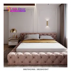 A closer look at one of our custom-built beds, designed to be a statement piece. The entire frame, from the headboard to the base, is fully upholstered in a dusty pink fabric with deep button tufting. This technique adds a layer of luxurious texture and visual interest to the bedroom.