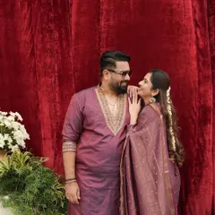 A sweet, candid moment between Tharun and Sonal. The coordinated wine-colored outfits look so rich and beautiful against the red velvet backdrop.