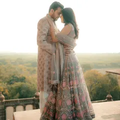A romantic portrait of a couple overlooking a lush green valley from a stone balcony. The soft, golden hour light adds a dreamy quality to this elegant pre-wedding photograph.