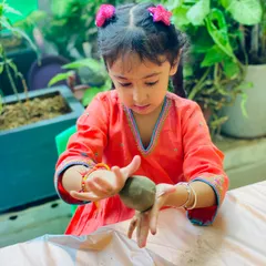 The concentration on her face is priceless! Each child gets to connect with the material at their own pace, feeling the texture of the clay as they create something meaningful.