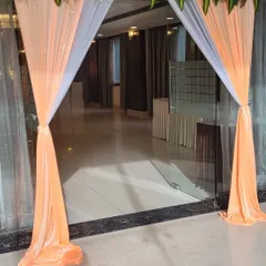 Even a simple entrance can be beautiful. For this event, we used peach and white fabric drapes with a floral header to create a soft and welcoming entryway for guests.