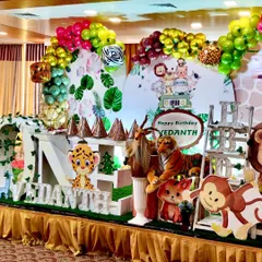 A wider angle of the jungle theme, showcasing the detailed backdrop with tropical leaves and a custom "Happy Birthday" sign. The arrangement includes multiple character cutouts and themed props to create a full and lively scene.