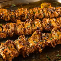 Freshly grilled chicken kebabs on skewers, captured for Punjab Grill. The focus is on the char marks and juicy texture, making it an ideal shot for a barbecue and tandoori menu.