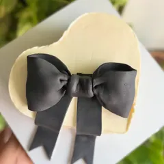 Minimal. Chic. Timeless. A heart-shaped buttercream cake with a dramatic, oversized black fondant bow, perfect for a modern and stylish Valentine's or anniversary gift.