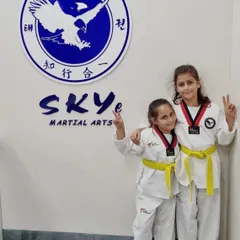 Success and smiles after a belt promotion event. These sisters celebrate their new yellow belts, a testament to their hard work and progress in our Taekwondo program.