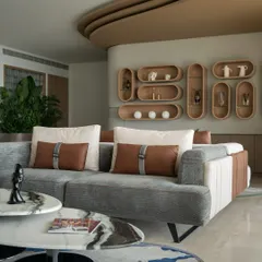 This view showcases the custom sofa with its blend of grey corduroy, smooth leather, and cream fabric. The layered coffee tables with marble tops add a touch of elegance, while the custom rug introduces a splash of color and artistry to the floor.