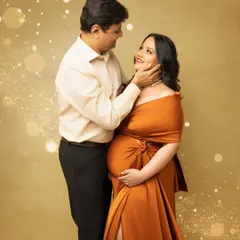 A tender moment between an expecting couple. The husband gently caresses his wife's face as she glows in a beautiful off-shoulder maternity gown.