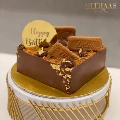 My Lotus Biscoff cake is a divine experience. This square chocolate cake is generously topped with Biscoff biscuits, Biscoff crumble, and dollops of rich frosting, all accented with edible gold leaf for a touch of luxury.