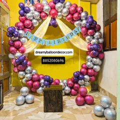 This vibrant balloon ring in metallic silver, purple, and pink is a great photo booth for a birthday party. The 'Happy Birthday' banner and fairy lights add a festive touch.