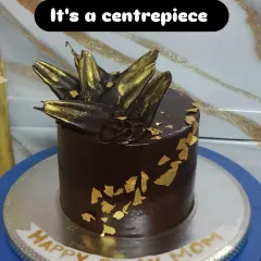 An elegant dark chocolate cake with abstract gold-dusted chocolate shards and edible gold leaf. It's a centerpiece that is both deep and luxurious.