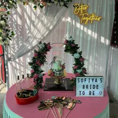 A complete bridal shower setup featuring a cake table, fun props, and a personalized light-box sign. The backdrop includes a floral arch and a "Better Together" neon sign.