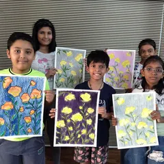 A group of students showing their beautiful flower drawings made with oil pastels. Each child has created a unique color combination, learning about composition and background design.