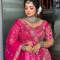 A soft, romantic reception look with a focus on pink tones for the eyes and a classic updo with a white flower.