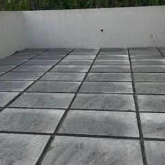 A completed patio using large, square Sadahalli stone slabs. The dark grout lines create a clean, geometric look that complements modern architecture.