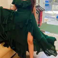 This custom emerald green off-shoulder gown is designed to impress. The combination of a fitted bodice, flowing ruffles, and a dramatic slit makes it a perfect choice for a formal party or wedding reception.