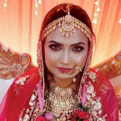 A beautiful bride ready for her big day. The makeup features a blend of pink and gold tones, which adds a soft, romantic feel to the traditional red and gold bridal attire.