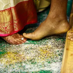 A detail shot of a wedding ritual, where the bride's foot, adorned with a toe ring, touches the groom's.