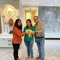 Handing over the keys to this beautiful home. In the background, you can see the finished stone texture TV wall and the elegant pooja unit we designed, all ready for the clients to enjoy.