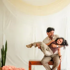 A playful studio moment with a father joyfully lifting his daughter in his arms. We use a simple, light-filled setup to keep the focus entirely on your family's interaction and happiness.