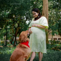 A quiet moment between a mom-to-be and her loyal companion. This outdoor shot beautifully captures the bond they share as they wait for the new family member.
