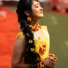 The bride basking in the sun, showing off her gorgeous Haldi look with a floral braid and jewelry.