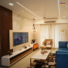 This living room setup shows how we balance different elements. A plush blue sofa, a marble and gold coffee table, and a feature wall with wooden fluting and marble create a look that is modern, luxurious, and well-balanced.