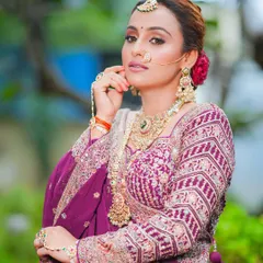 This royal bridal look in a stunning purple lehenga is all about poise and elegance. The makeup is designed to complement the rich outfit and heavy jewelry.
