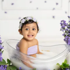 A sweet smile from a baby girl enjoying her lavender-themed milk bath. The soft purple flowers create a calm and beautiful setting for her portraits.
