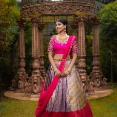 Capturing the joy and elegance of a traditional outfit. This image highlights the intricate details of the hand-embellished blouse and the flow of the pleated skirt against a rich, architectural background.