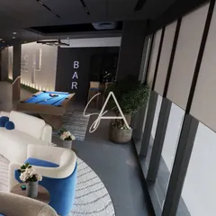 The lounge area of the wellness center, featuring a pool table and comfortable seating. Large windows provide ample natural light, while the modern furniture and 'BAR' sign create a relaxed, club-like vibe.
