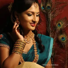 A creative photoshoot inspired by traditional art. The model's makeup is rich and expressive, complemented by peacock feathers and classic jewelry.