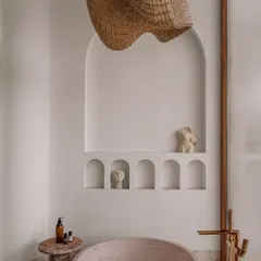 The bathtub area in the junior master ensuite, featuring a freestanding tub, a woven pendant light, and a series of arched niches for displaying art and personal items.
