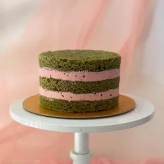 A look inside the matcha strawberry cake. This "naked" view reveals the layers of vibrant green matcha sponge and fresh strawberry buttercream filling.