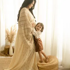 A tender moment between a mother and her daughter during a maternity shoot. The little girl hugs her mom's baby bump, excited to meet her new sibling.