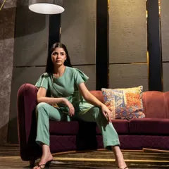 A model seated on a luxurious sofa in a mint green co-ord set. This lifestyle-oriented studio shot helps customers imagine wearing the outfit in a sophisticated, real-world setting.