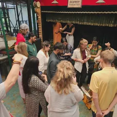 A group of students gathers around a small stage for a hands-on puppet demonstration. These intimate sessions allow for close interaction and give participants a real feel for how the puppets work.