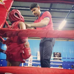 In the corner with a young fighter, making sure her headgear is secure before the match. Safety and proper preparation are my top priorities as a coach.