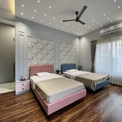 A shared kids' bedroom designed with a sophisticated yet playful touch. The room features individual twin beds in pastel pink and blue, set against a feature wall with elegant molding and a charming nature-themed wallpaper.