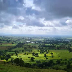 The view from a high vantage point, showing the sprawling green carpet of the Maharashtra countryside during the monsoon.