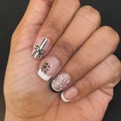 A minimalist take on festive nails. This design features a clean French manicure with subtle, hand-painted Christmas details like a gift bow and a snowflake for a touch of holiday cheer.
