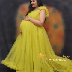 A radiant studio portrait featuring our sunny yellow ruffled gown. The soft tulle and delicate ruffles on the sleeves create a gentle, flattering look that beautifully frames the baby bump.