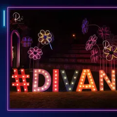 A fun and colorful photo op for a neon party, featuring a large marquee sign with the event's hashtag and whimsical neon flower sculptures.