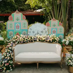 A perfect photo opportunity with a custom-designed backdrop for a Mehendi ceremony. The pastel-colored panels with traditional motifs and lush floral arrangements create a beautiful and memorable setting.